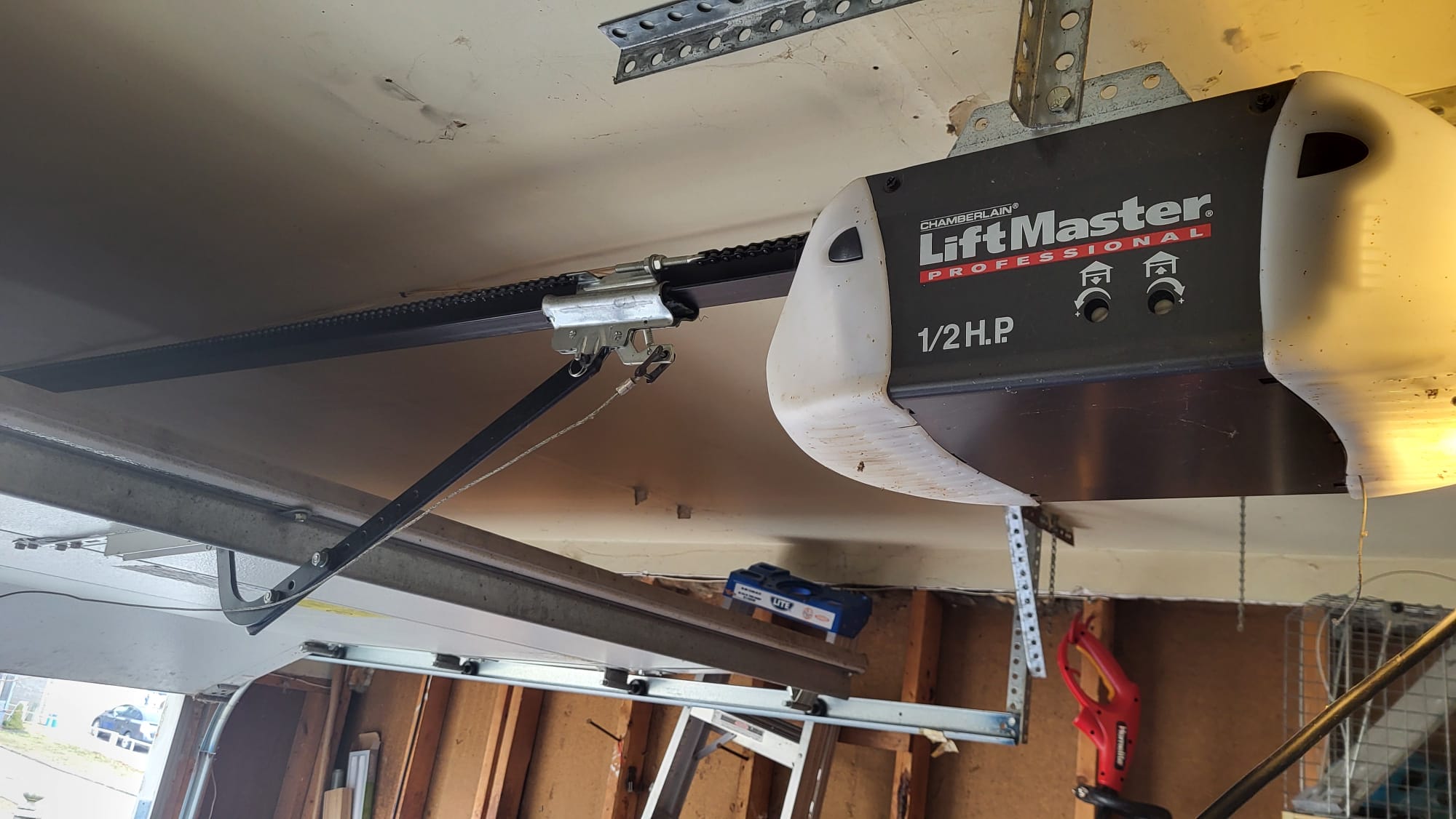 A LiftMaster garage door opener mounted on a garage ceiling with a chain drive mechanism for garage doors.